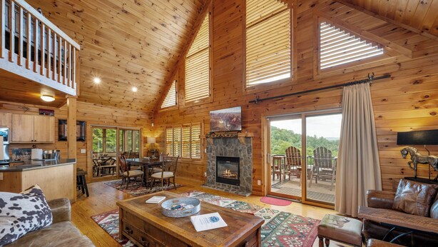 A log cabin interior with a fireplace, dining area, and a view of the outdoors. - Brook Haven: Private Cabin, Great Views, Hot Tub, WiFi, Fireplace (Ferguson)