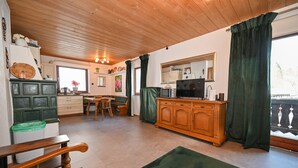 A cozy kitchen with wooden cabinets, a dining table, and a green upholstered bench. - BUDGET Chalet Alpine - Apartment B (Zell am See)