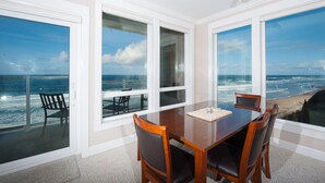 A dining area with a view of the ocean, a 'RELAX' sign, and a table with chairs. - Promo! Third Floor Corner Condo, Oceanfront, Private Hot Tub, Pool, Free Wifi! (Lincoln City)