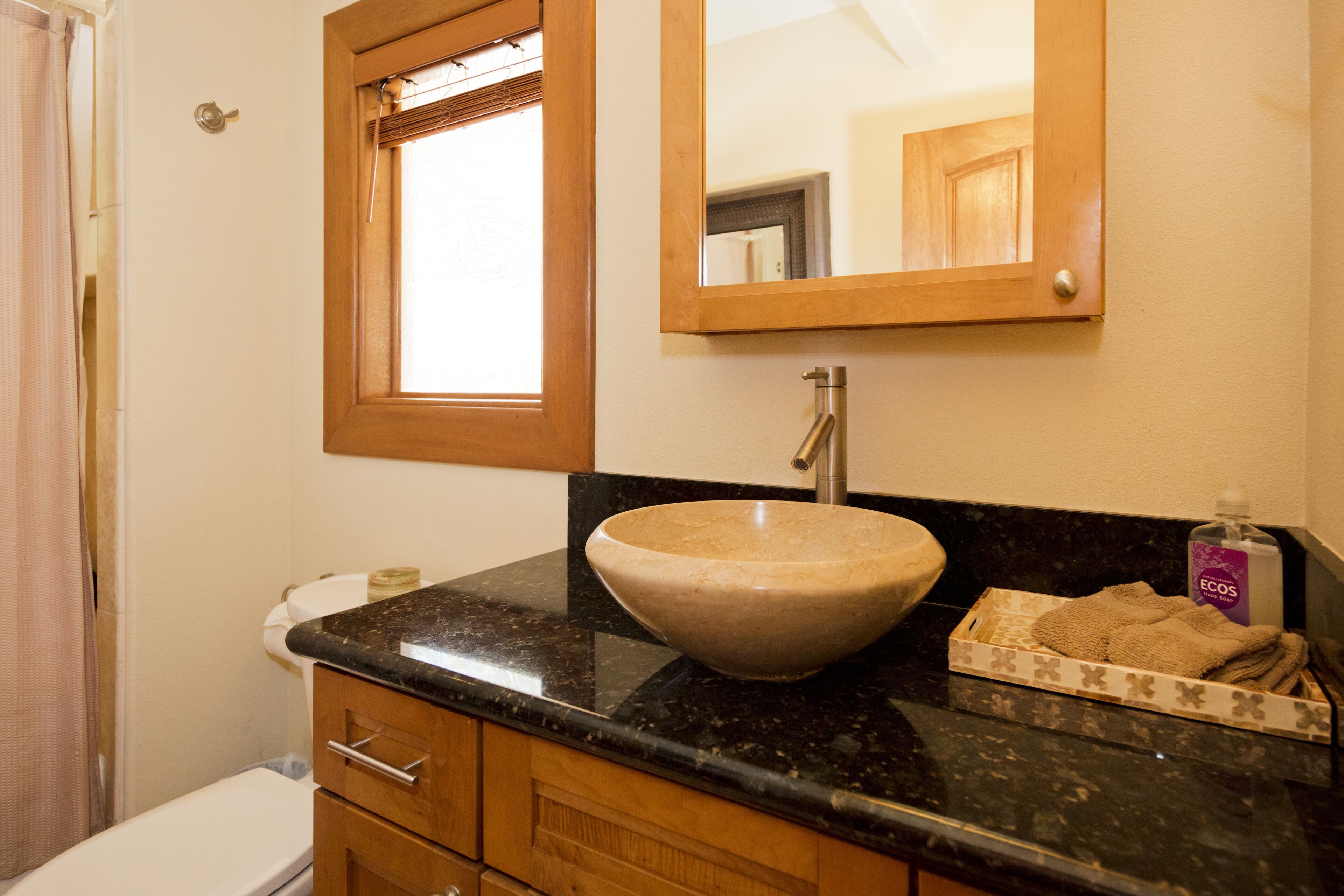 A bathroom with a wooden vanity, a large mirror, a sink, and a towel rack.