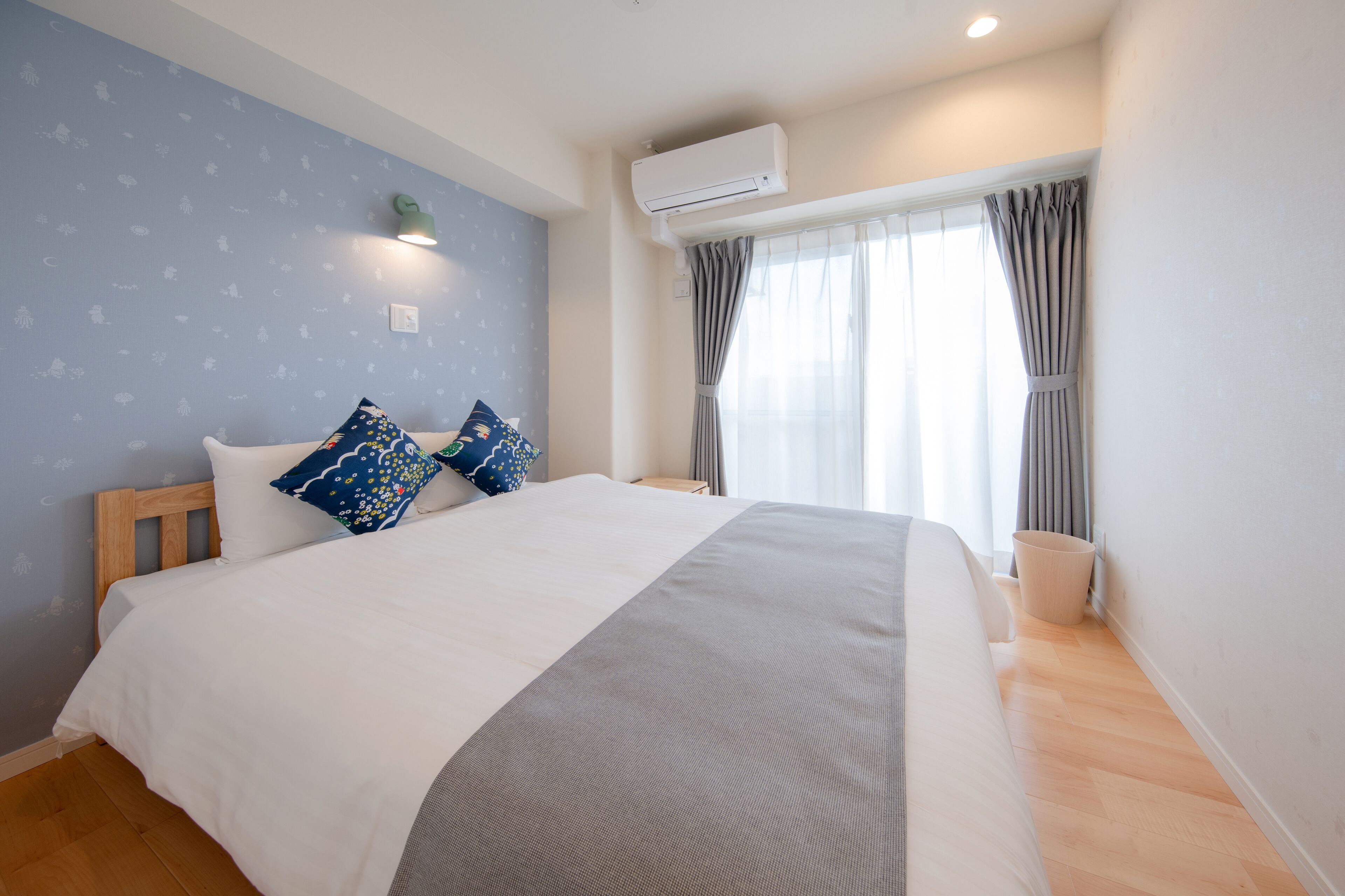 Une chambre à coucher avec un grand lit, une table de chevet, un appareil de climatisation et une fenêtre avec des rideaux.