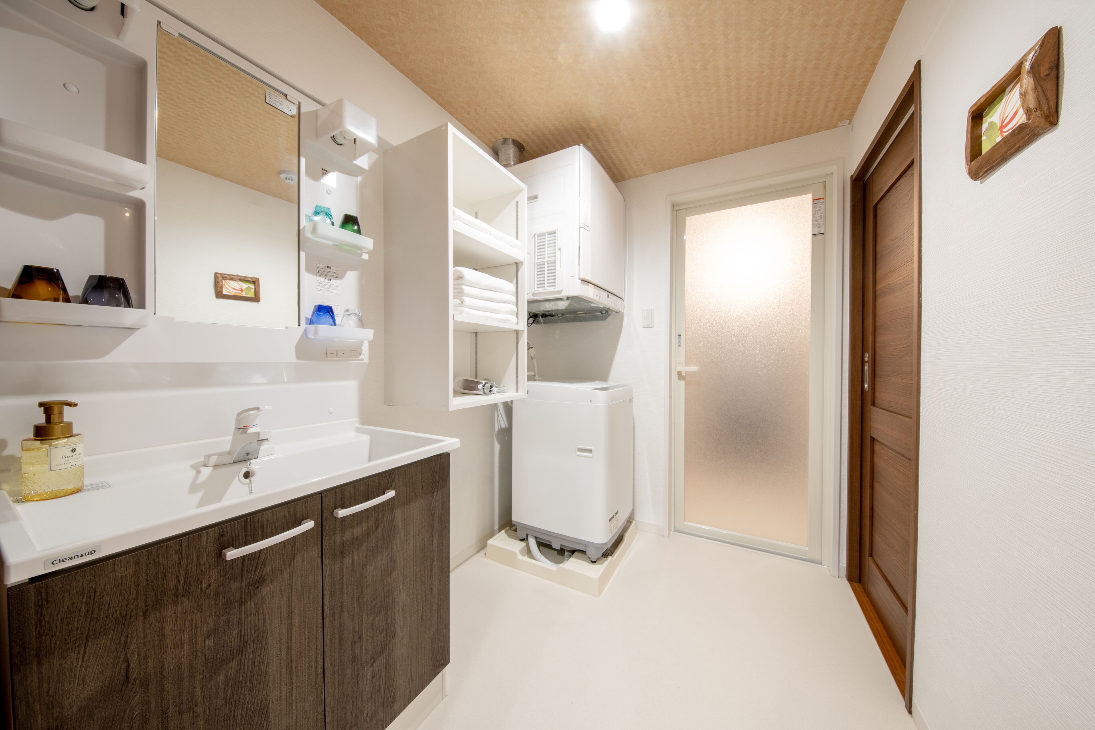 A modern bathroom with a white sink, dark wooden cabinets, a built-in mirror, and a white heater.