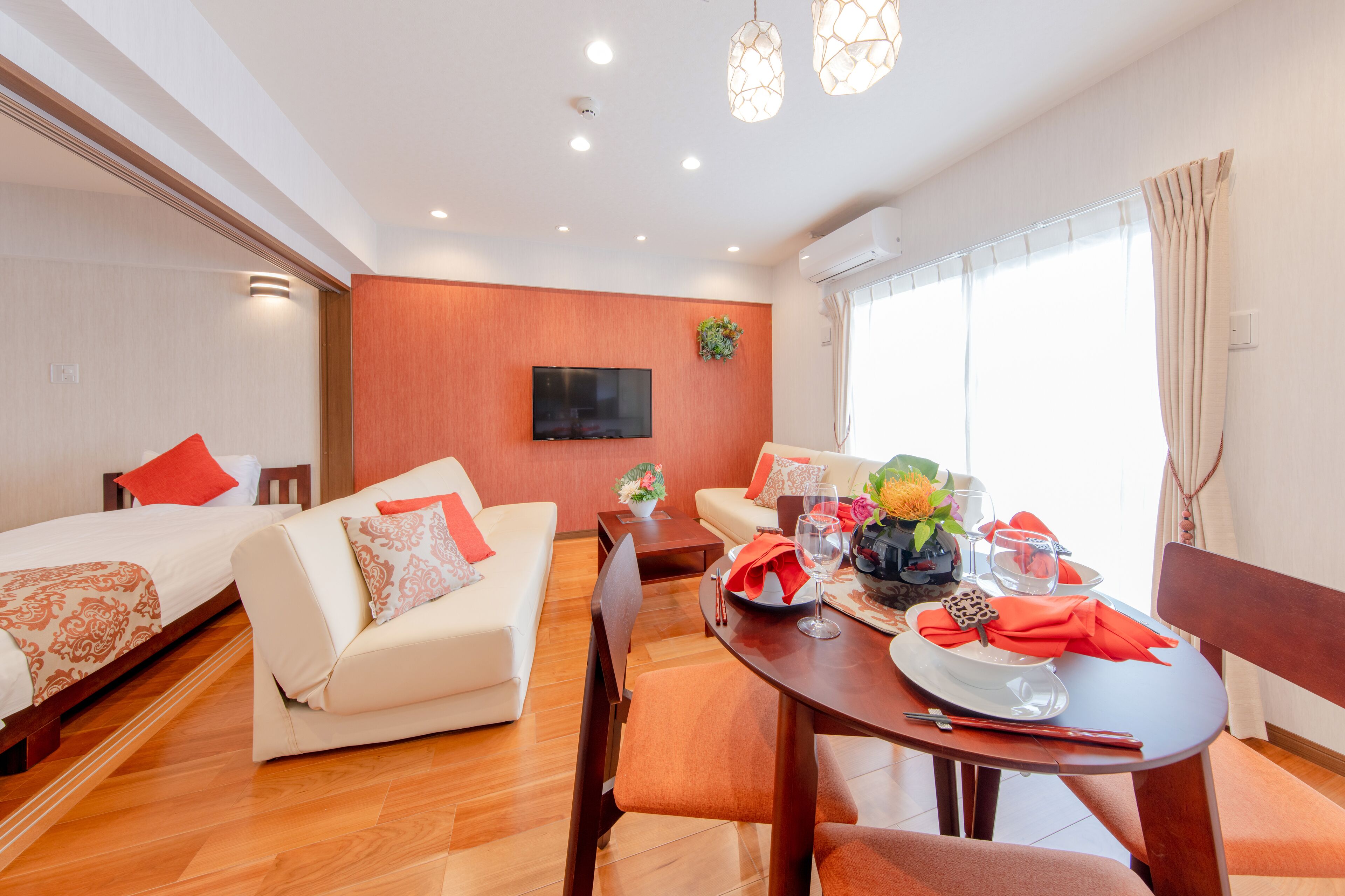 A modern hotel room with a dining area, a sofa, a bed, and a TV.