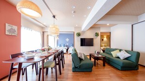 Ein modernes Wohnzimmer mit Essbereich, einem grünen Sofa und Holzböden.
