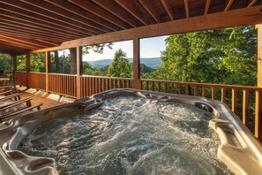 A hot tub under a wooden deck with a view of trees and mountains. - Beautiful Mtn View! Pool Table, Arcade Game, Hot Tub, Pool, Putt Putt & Fishing (Sevierville)