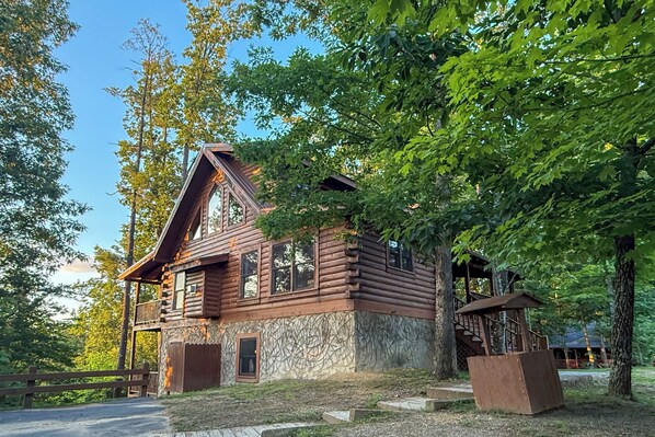 A rustic log cabin with a balcony, surrounded by trees. - Beautiful Mtn View! Pool Table, Arcade Game, Hot Tub, Pool, Putt Putt & Fishing (Sevierville)