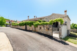 A stone building with a tiled roof, a gated entrance, and a paved road in front. - Casa de Stalla with private pool in Poreč (Porec)