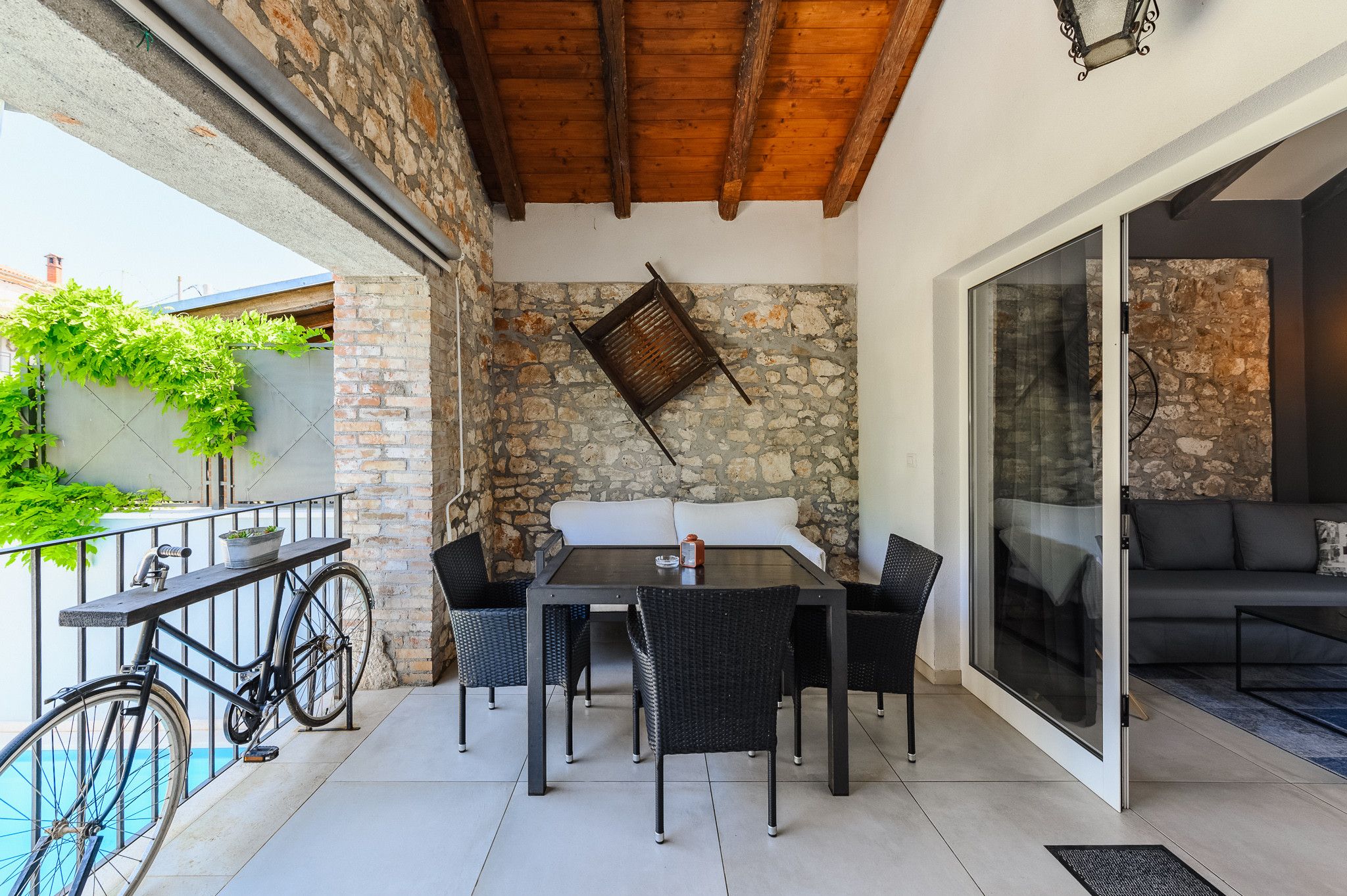 An outdoor patio with a table and chairs, a bicycle, and a stone wall.