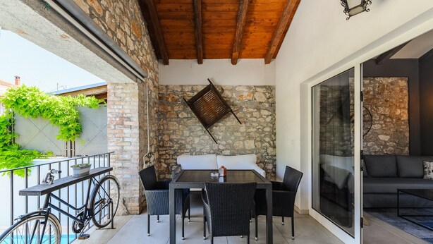 An outdoor patio with a table and chairs, a bicycle, and a stone wall.