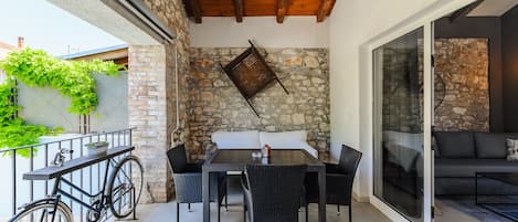 An outdoor patio with a table and chairs, a bicycle, and a stone wall.
