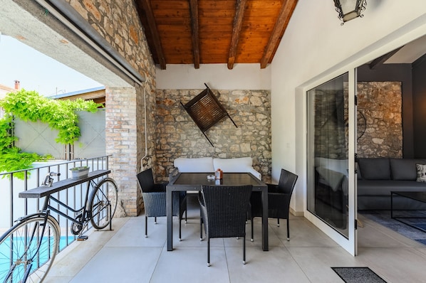 Une terrasse extérieure avec une table et des chaises, un vélo et un mur en pierre.