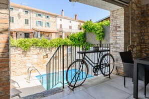 Un balcon avec une piscine, un vélo et une table avec des chaises.