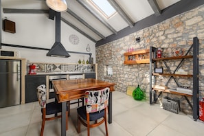 A modern kitchen with a stone wall, a wooden dining table, and a built-in shelf with various items.