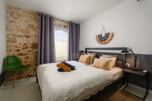 Ein Schlafzimmer mit Steinwand, einem Bett mit Kopfteil, einem Nachttisch, einer Lampe, einem Sessel und einer Wanddekoration.