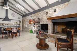 A cozy interior with a stone wall, a fireplace, and a dining area with wooden furniture. - Villa Casa de Stalla with pool in Poreč (Porec)