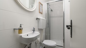 A bathroom with a white sink, toilet, and a glass shower enclosure.