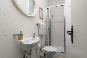 Une salle de bain avec un lavabo blanc, des toilettes et une cabine de douche en verre.