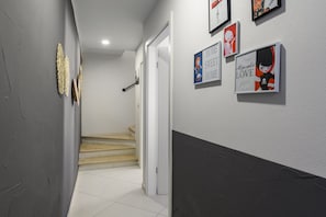 A hallway with a staircase leading to another room, decorated with framed posters on the wall.