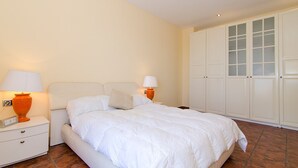 A bedroom with a bed, nightstands, a lamp, and a wardrobe. - Club Villamar - Modern, spaciously designed holiday villa that can accommodate 17 people, with pr... (Lloret de Mar)