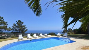 A swimming pool with white lounge chairs and a view of the sea. - Club Villamar - Modern, spaciously designed holiday villa that can accommodate 17 people, with pr... (Lloret de Mar)