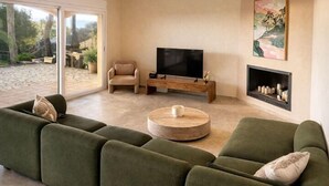 A modern living room with a sectional sofa, a TV, and a fireplace. - Club Villamar - Modern, spaciously designed holiday villa that can accommodate 17 people, with pr... (Lloret de Mar)