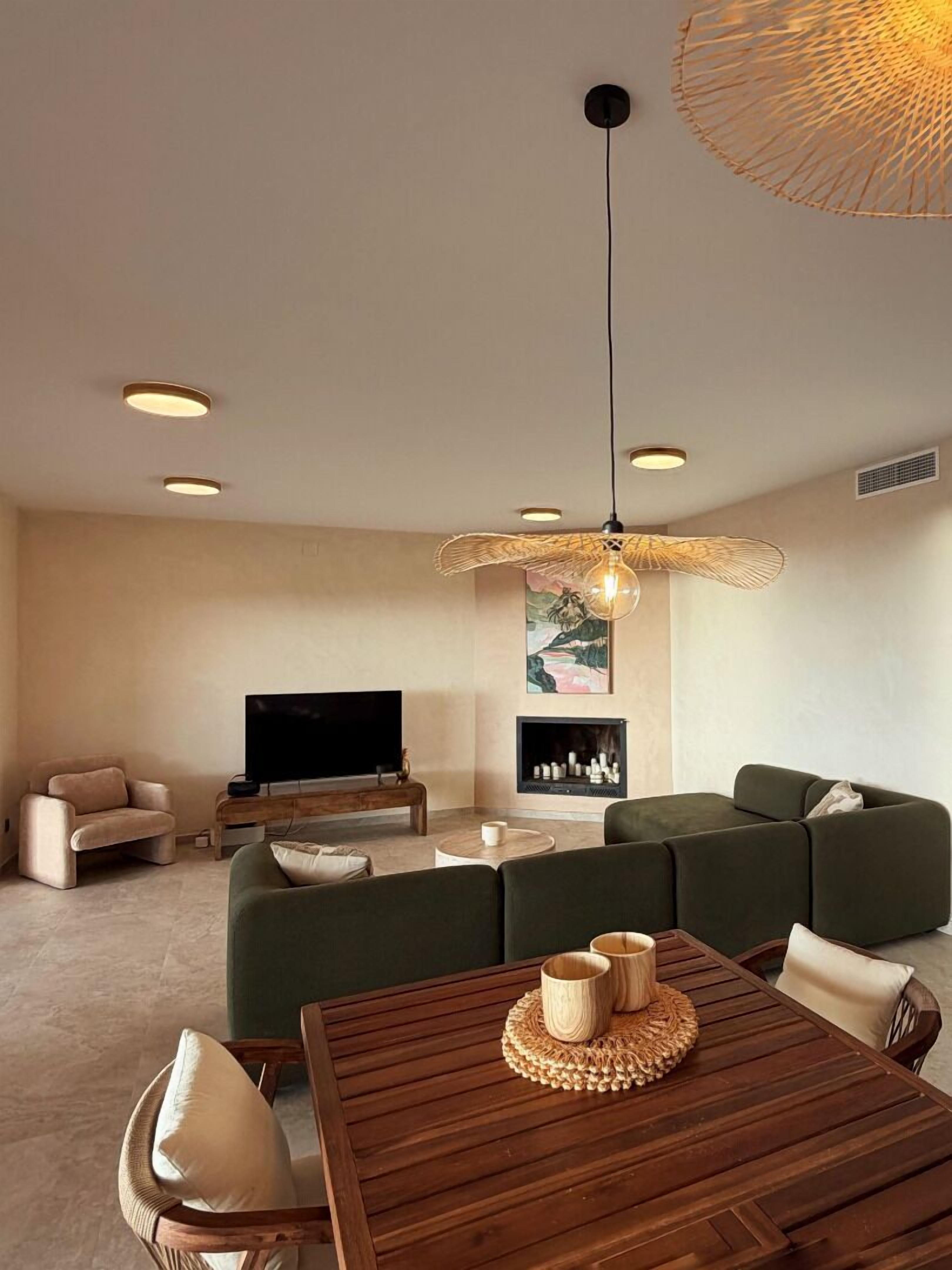 A modern living room with a sectional sofa, a flat-screen TV, a wooden coffee table, and a dining table with chairs.