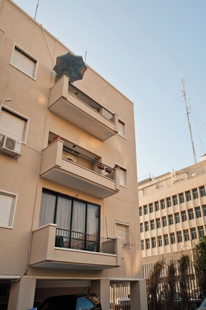 Un edificio a più piani con balconi, condizionatori d'aria e un cielo sereno.