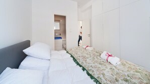 Une chambre d’hôtel avec un lit, une armoire et une salle de bain visible à travers une porte ouverte.