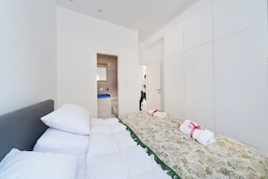 Una camera d'albergo con un letto, un armadio e un bagno visibile attraverso una porta aperta.