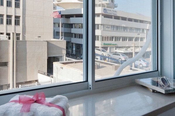A hotel room with a large window overlooking a parking garage and a building with an American flag.