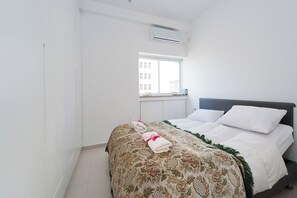A hotel room with a bed, a window, and an air conditioning unit.