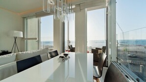 Un espace repas moderne avec une grande table, des chaises et une vue sur la mer.