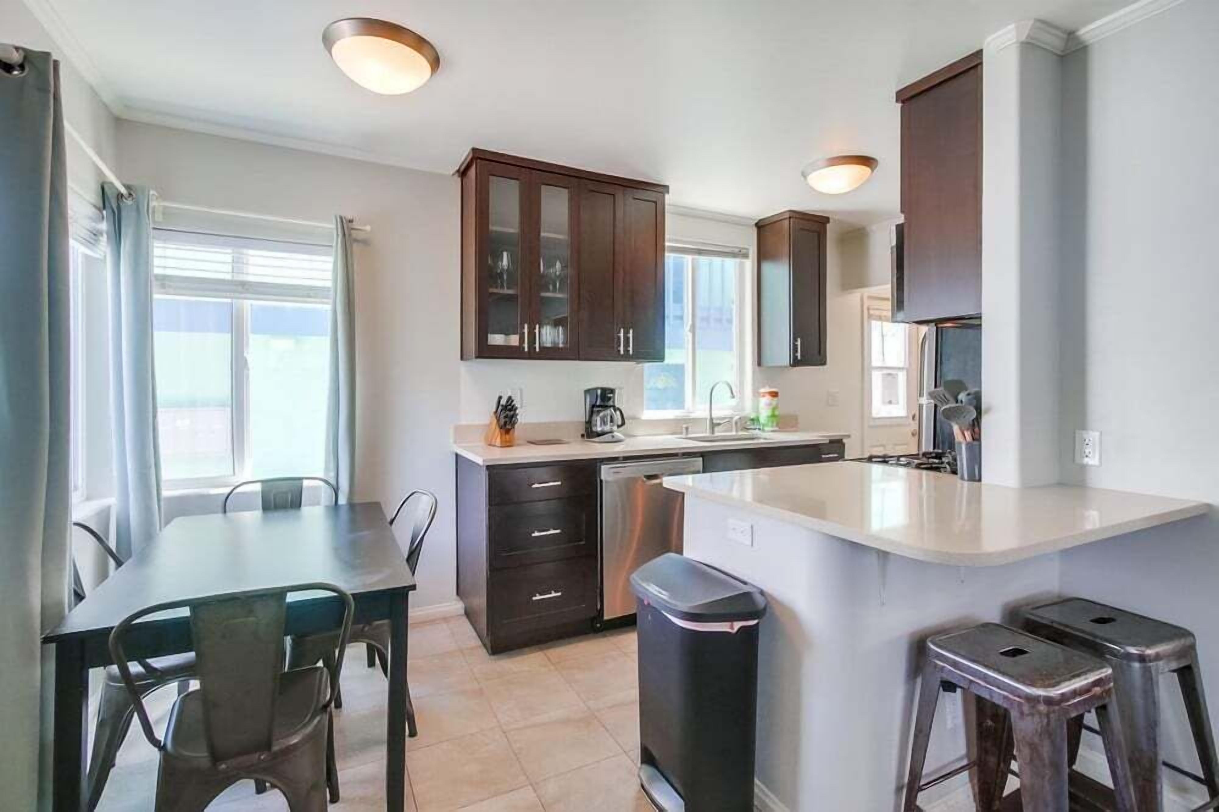 Une cuisine moderne avec des meubles de rangement en bois foncé, un îlot central et un coin repas avec des chaises.