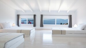 A modern hotel room with two beds, large windows with curtains, and a view of the sea and mountains. - Villa Koumaria - Secluded Elegance with Amazing Sea Views & Infinity Pool (Sivota)