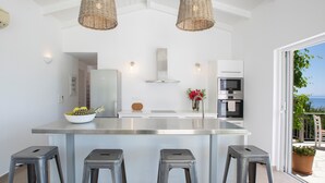 A modern kitchen with a central island, stainless steel appliances, and a view of the outdoors. - Villa Koumaria - Secluded Elegance with Amazing Sea Views & Infinity Pool (Sivota)