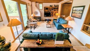 Ein gemütliches Wohnzimmer mit Kamin, blauen Sofas und einem Holztisch.