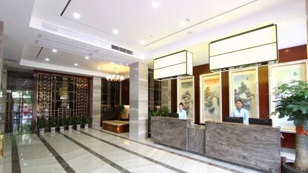 A hotel reception area with a marble floor, a reception desk, and a decorative wall with plants. - Shenzhen Hanlinxuan Business Hotel (Shenzhen)