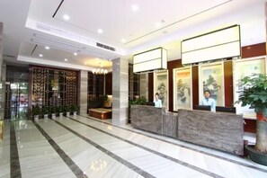Ein Hotel-Empfangsbereich mit Marmorboden, einer Rezeption und einer Wanddekoration mit Pflanzen.