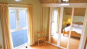 Une chambre avec un lit, une chaise et une grande fenêtre donnant sur l’eau.