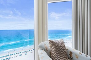 A room with a large window overlooking a beach.