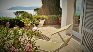 A patio with a white chair, a hammock, and a view of the sea and mountains. - Scrittore2 - Scrittore2 Villa Fiore (Capoliveri)