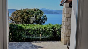 A stone patio leading to a door with a view of a lake and mountains. - Scrittore2 - Scrittore2 Villa Fiore (Capoliveri)