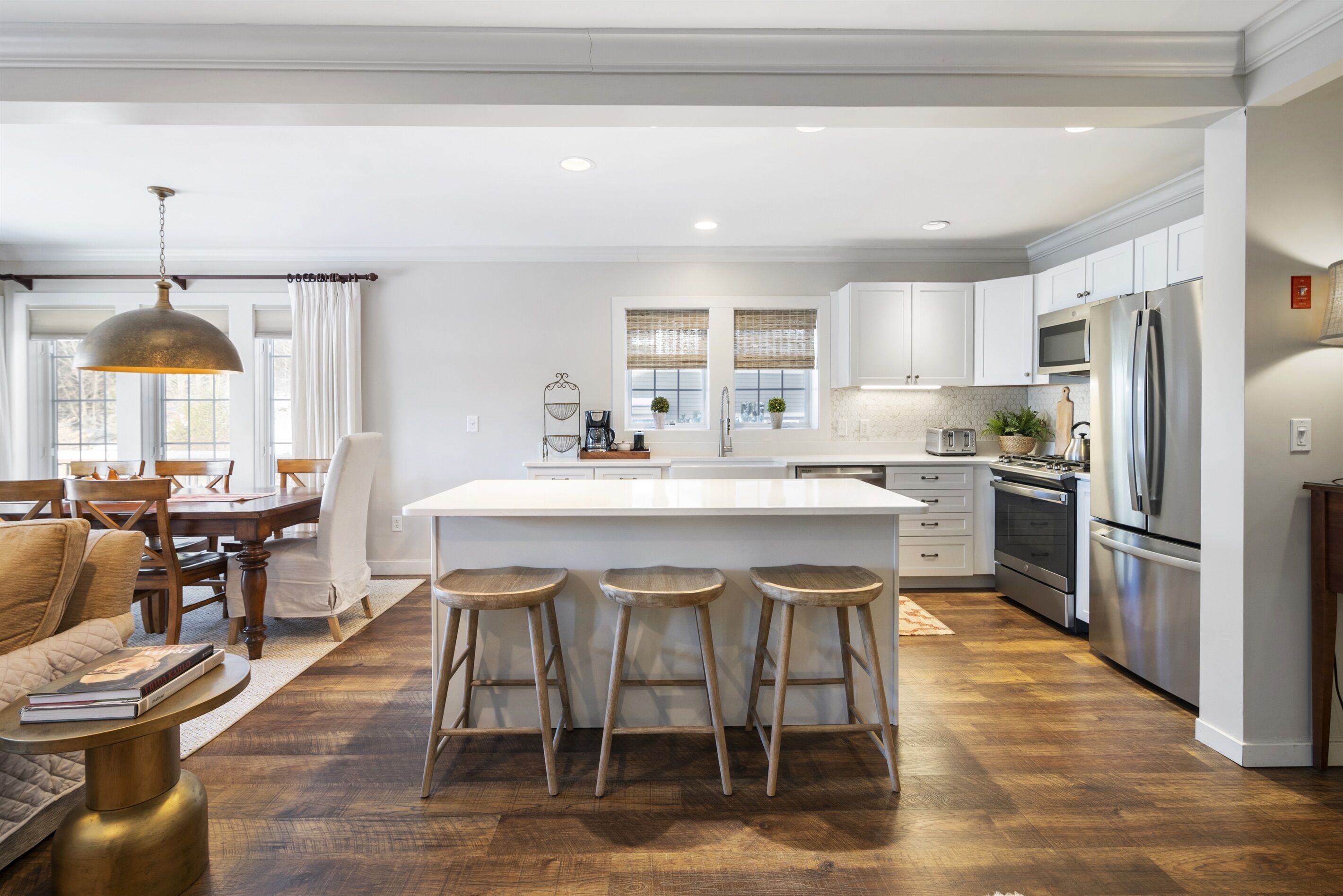 A modern kitchen with a central island, bar stools, and stainless steel appliances.