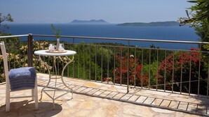 A balcony with a table, chair, and a view of the sea. - Villa NISI – Stylish Sea-View Retreat with Pool & Easy Access (sivota)