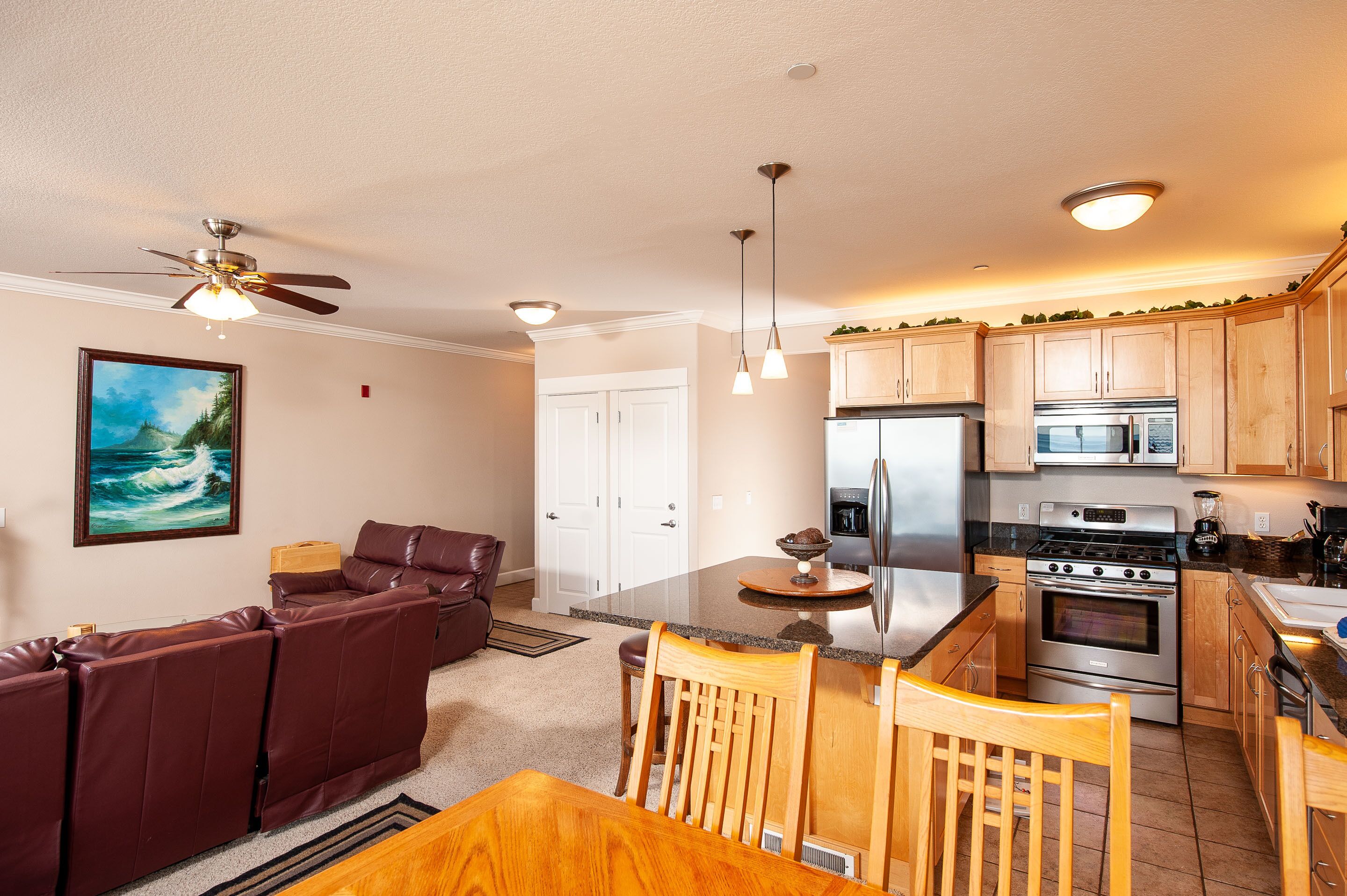 A modern kitchen with a central island, stainless steel appliances, and wooden cabinets.