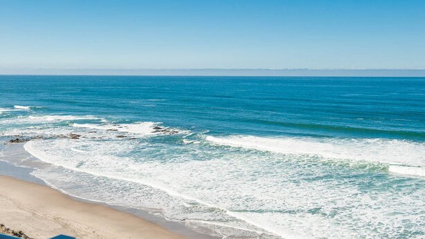 Een strand met helderblauw water en een zandstrand.