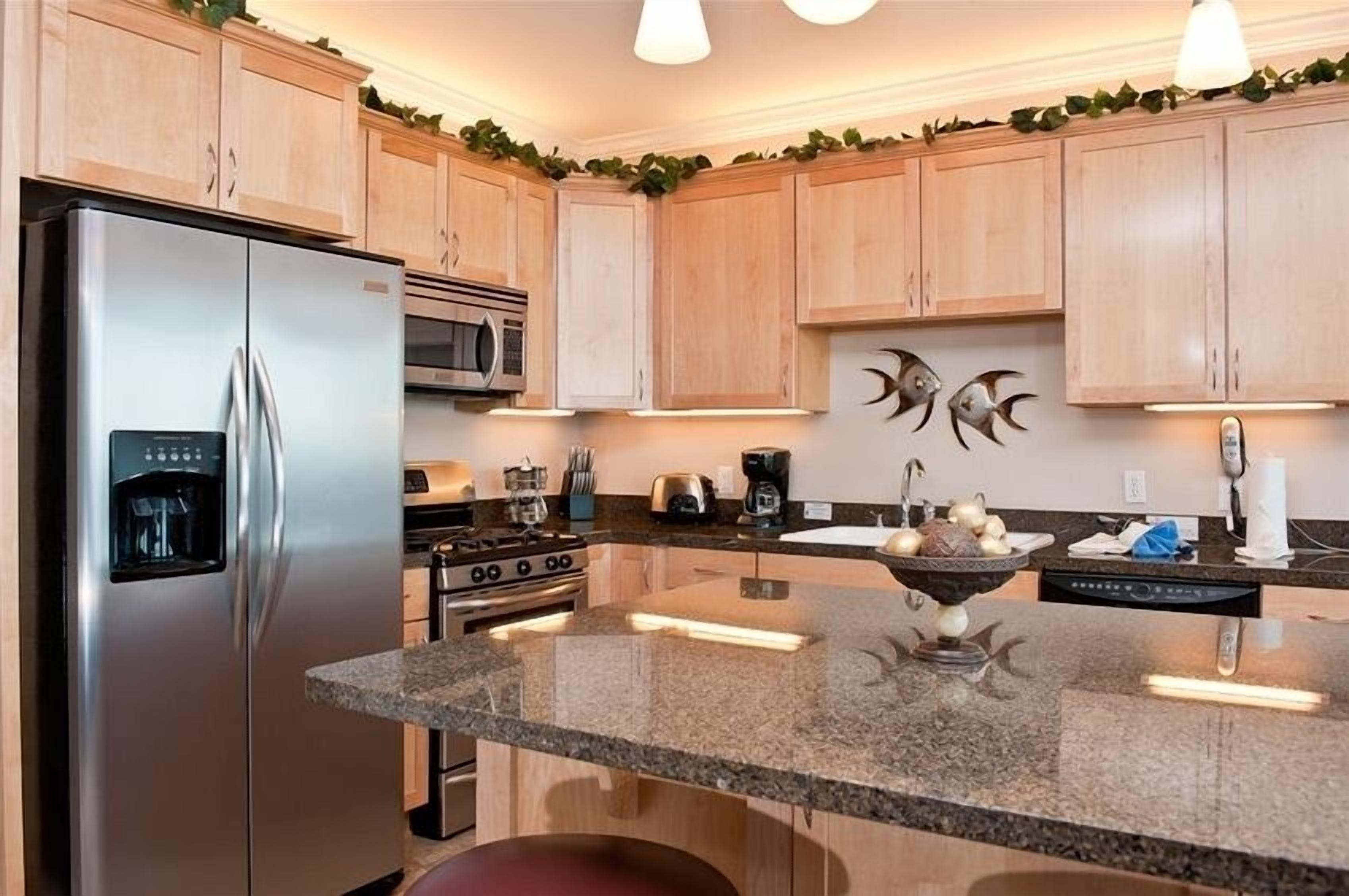 A modern kitchen with wooden cabinets, stainless steel appliances, granite countertops, and decorative fish wall art.