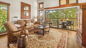 A spacious living room with a large window, a sofa, a coffee table, and a decorative rug.