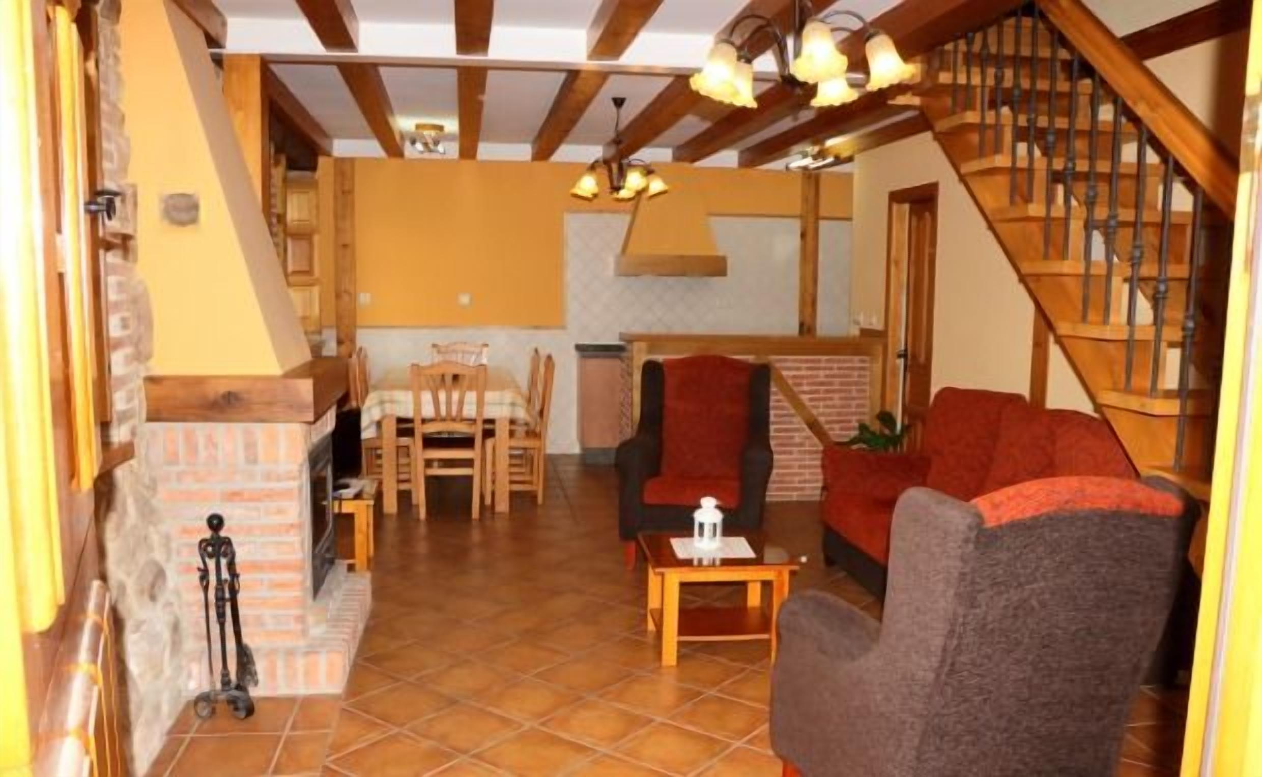 Ein gemütliches Wohnzimmer mit Kamin, einem Essbereich mit Stühlen und einer Treppe.