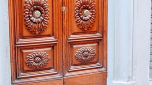 Une porte à deux battants en bois, ornée de motifs floraux complexes et dotée d’une poignée de porte en laiton.